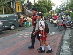 Berikan Rasa Aman, Personil Polsek Gianyar Bantu Anak Sekolah Menyebrang Jalan.